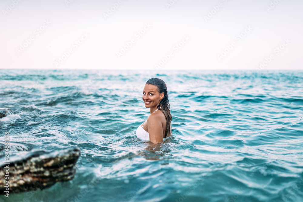 Gorgeous woman standing in the sea water. Looking at camera. Genuine emotions.
