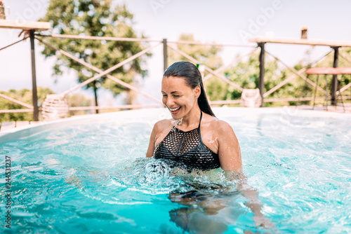 Beautiful young woman enjoying in a swimming pool. Real emotions.
