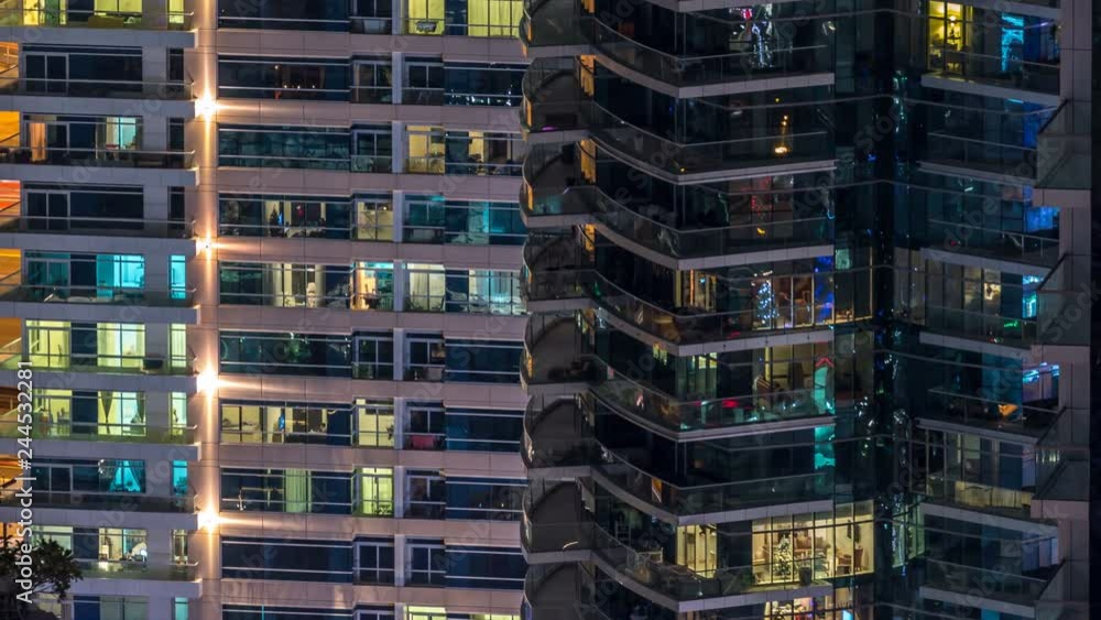 Glowing windows in multistory modern glass and metal residential building light up at night timelapse. Glowing windows in multistory modern glass and metal residential building light up at night timelapse.