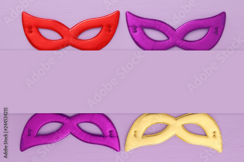 carnival party celebration concept with colorful masks over purple wooden background. Top view. Flat lay.