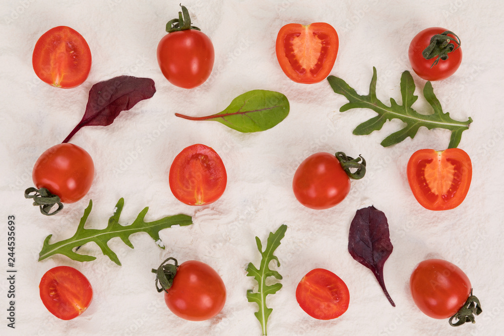Whole and halved tomatoes on flour, arugula and basil. Whole and halved tomatoes on flour, arugula and basil.