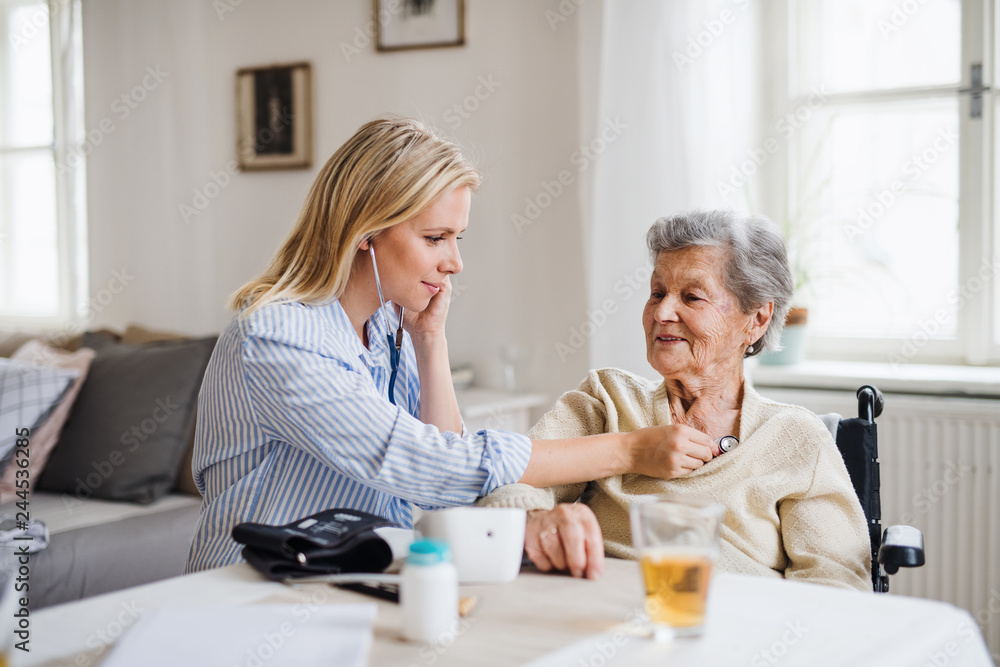 A health visitor examining a senior woman with a stethoscope at home. A health visitor examining a senior woman with a stethoscope at home.