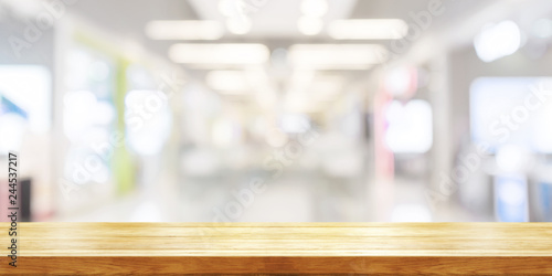 Empty wooden table top with blurred modern shopping mall background. Panoramic banner.