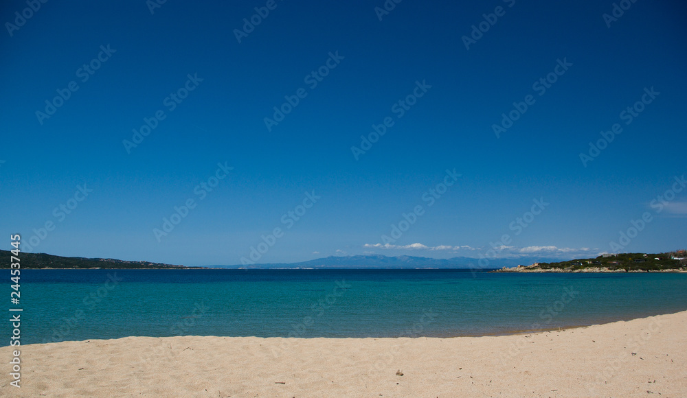 Splendida spiaggia tranquilla  con mare cristallino turchese e cielo blu a Porto Pollo, Sardegna. Sullo sfondo si vede la Corsica