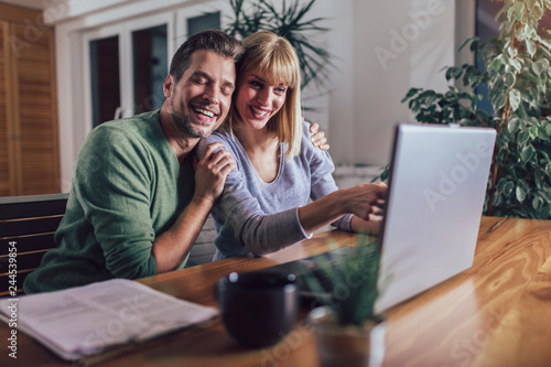Happy couple with laptop spending time together at home
