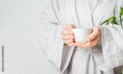 Close view of female hands holding teacup during tea ceremony with selective focus. Asian food theme background. Brewing and Drinking tea.