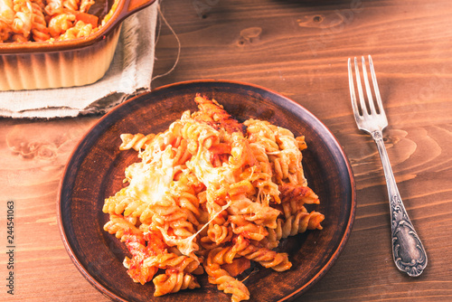 Traditional Italian pasta baked with mozzarella cheese and tomatoes on a plate and rustic background
