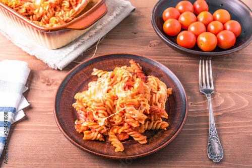 Traditional Italian pasta baked with mozzarella cheese and tomatoes on a plate and rustic background