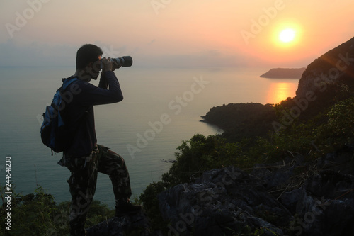 Silhouette of man climbing rock, Photographer on the mountain at sunrise