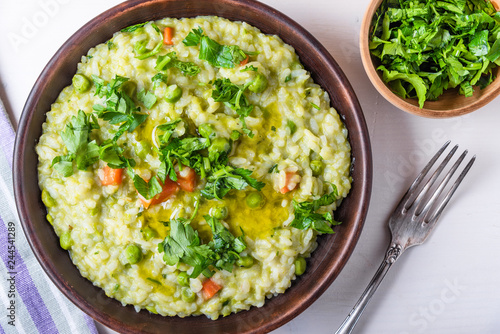 Traditional Italian vegetarian risotto with peas, carrots and parsley in rustic style, closeup