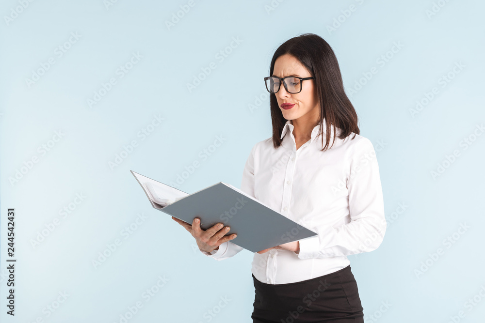 Confused emotional pregnant business woman isolated over blue wall background holding folder. Confused emotional pregnant business woman isolated over blue wall background holding folder.