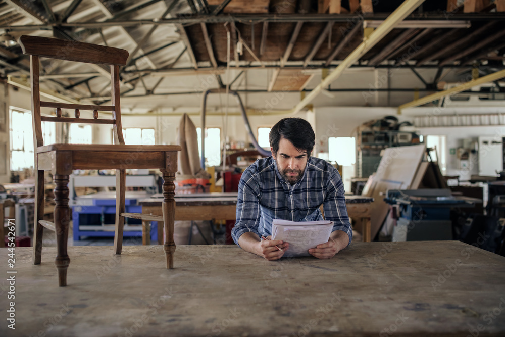 Woodworker creating a new chair design in his furniture workshop Woodworker creating a new chair design in his furniture workshop