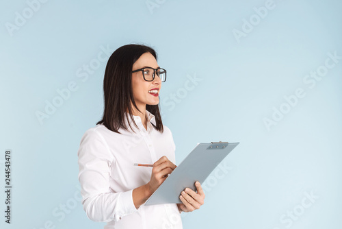 Pregnant business woman isolated over blue wall background holding clipboard.