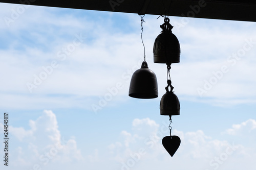 Silhouette Small brass bell hanging from roof in temple at north of thailand