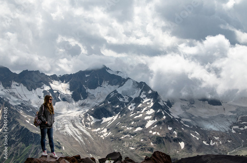girl stands on a rock against the backdrop of high mountains