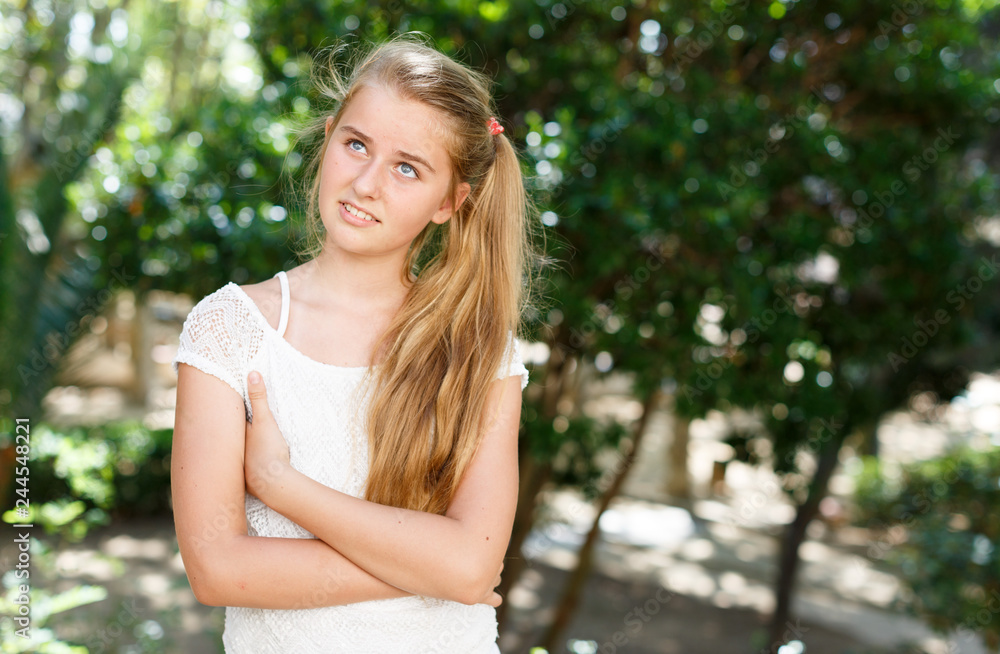 Portrait of  teenage cute girl standing in green park at sunny day