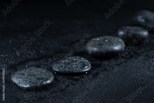 Zen stones with drops of dew on a black background