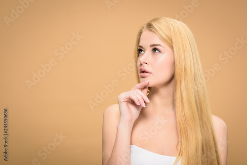 Pensive blonde girl looking up and touching chin