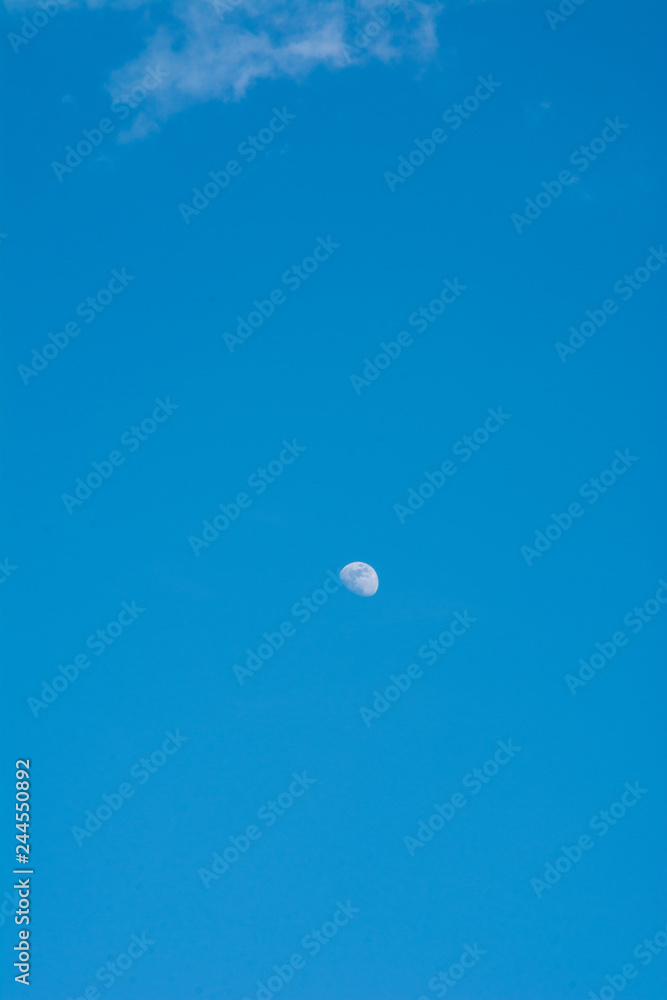 A beautiful moon on a daytime blue, magical sky with white clouds A beautiful moon on a daytime blue, magical sky with white clouds