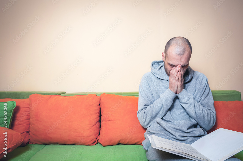 Young or middle age sick man in the casual clothes reading medic results on the papers from his doctor and realize that he have a cancer or other sickness Young or middle age sick man in the casual clothes reading medic results on the papers from his doctor and realize that he have a cancer or other sickness