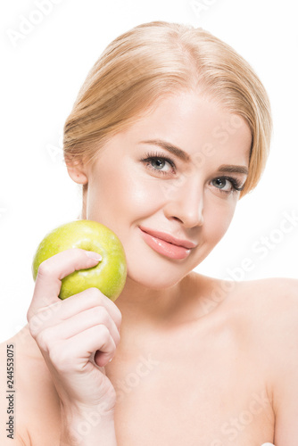 beautiful naked young woman holding fresh green apple and smiling at camera isolated on white