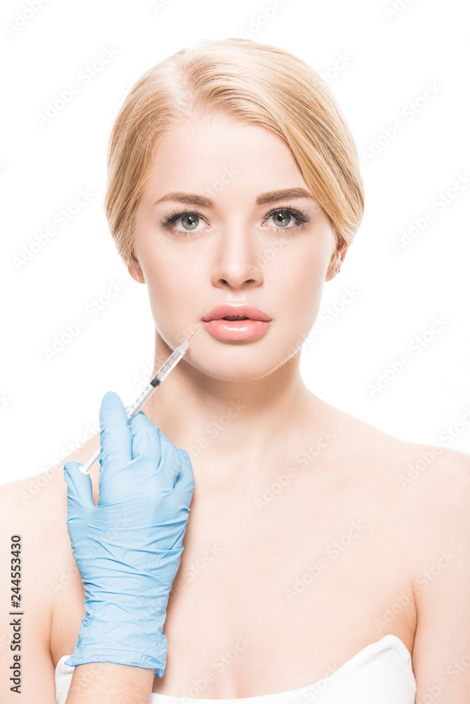 beautiful young woman receiving beauty injection in face and looking at camera isolated on white beautiful young woman receiving beauty injection in face and looking at camera isolated on white