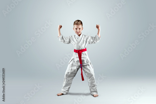 Creative background, a child in a white kimono in a fighting stance, on a light background. The concept of martial arts, karate, sports since childhood, discipline, first place, victory. copy space.