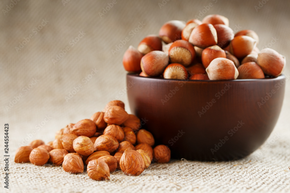 Peeled hazelnuts in a wooden, dark brown cup on a burlap cloth. Super Food, Raw. Peeled hazelnuts in a wooden, dark brown cup on a burlap cloth. Super Food, Raw.