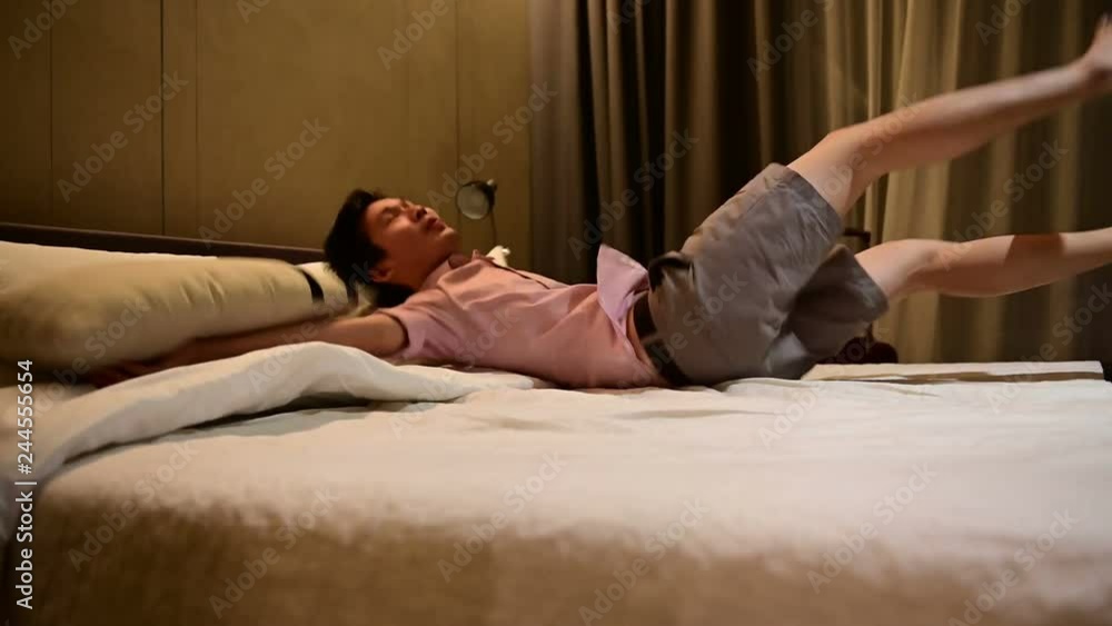 4K Asian tourist man walks into hotel room and jumping on bed after successful travel journey 4K Asian tourist man walks into hotel room and jumping on bed after successful travel journey