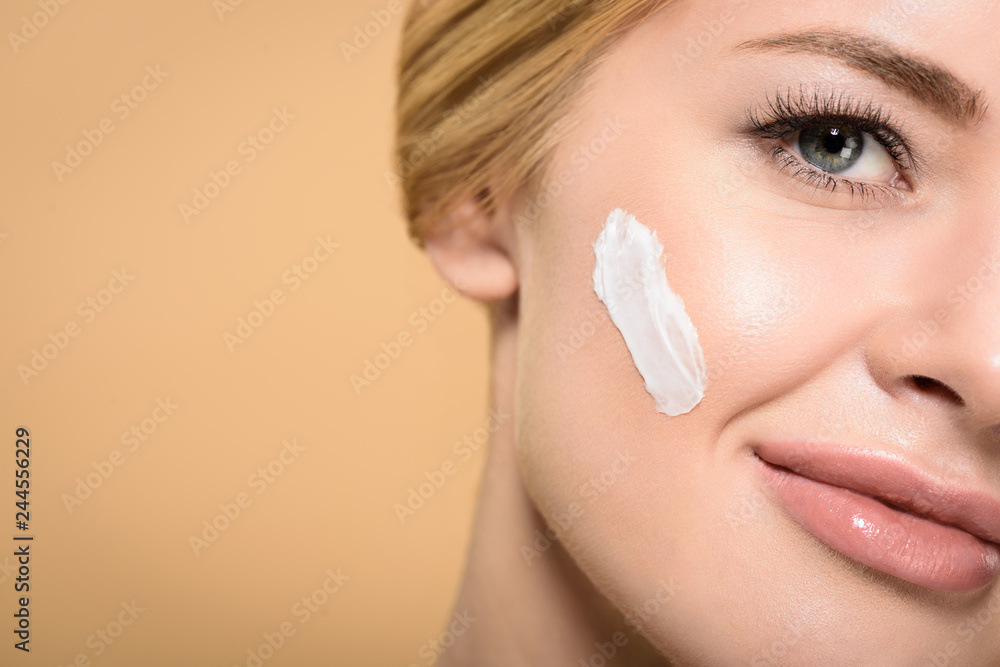 cropped shot of attractive young woman with cosmetic cream on face smiling at camera isolated on beige cropped shot of attractive young woman with cosmetic cream on face smiling at camera isolated on beige