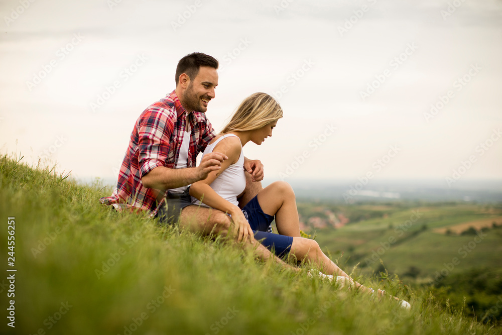 Loving couple sitting hugged on grass in the mountain Loving couple sitting hugged on grass in the mountain