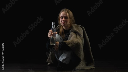 Lonely alcohol addicted woman drinking vodka from bottle, looking with hatred