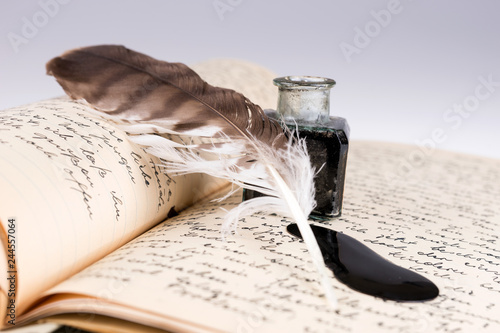 Old writing feather and ink spot with handwritten letter in background