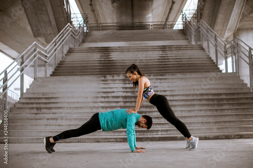 Athletic young couple doing stretching exercises together outdoor