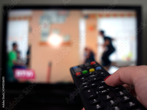 female hand with remote control on the background of the TV