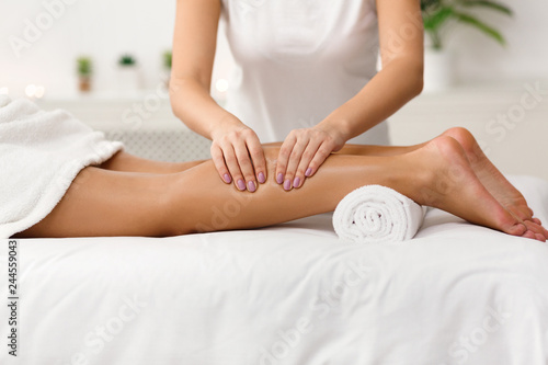 Massage therapist massaging woman calves in spa center