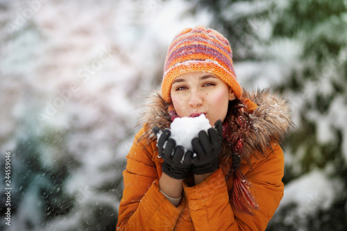 Fashion girl blowing snow in her hands, woman in winter enjoying cold weather in winter holiday, copy space