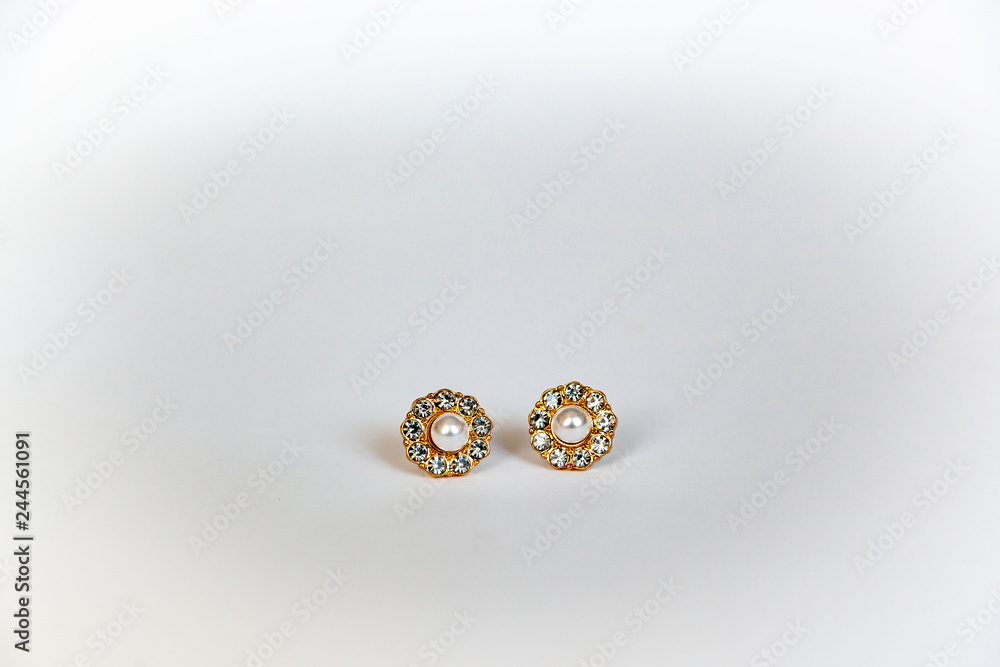 Jewelry gold earrings with gems and pearl on a white background Jewelry gold earrings with gems and pearl on a white background