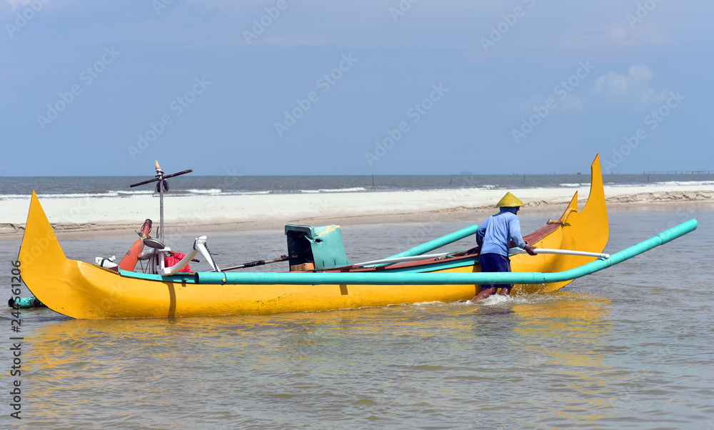 Fisherman pushing his fishing boat at the empty beach of Belitung Island, Indonesia Fisherman pushing his fishing boat at the empty beach of Belitung Island, Indonesia