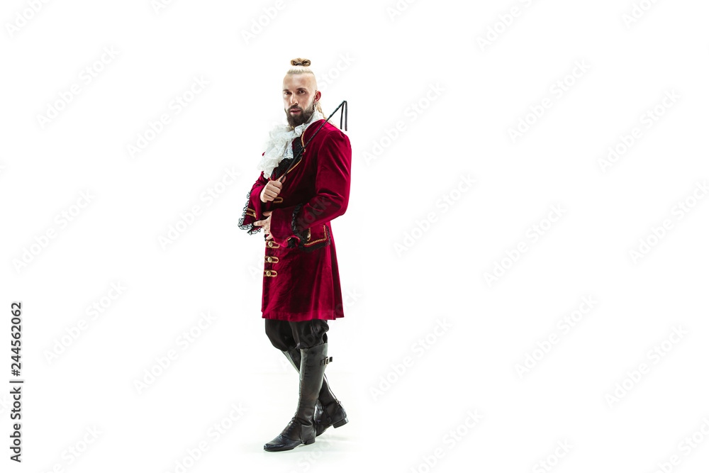 The young man wearing a traditional medieval costume of marquis posing at studio with whip. Fantasy, Antique, Renaissance concept