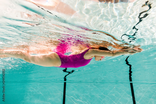 woman swimming underwater in swimming pool with blue water photo