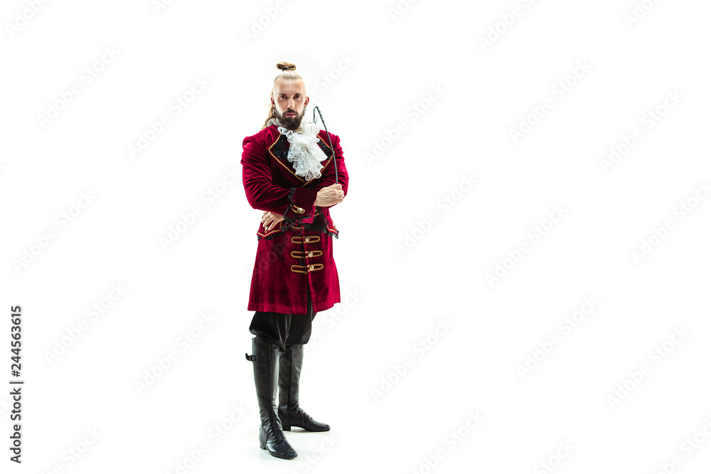 The young man wearing a traditional medieval costume of marquis posing at studio with whip. Fantasy, Antique, Renaissance concept The young man wearing a traditional medieval costume of marquis posing at studio with whip. Fantasy, Antique, Renaissance concept
