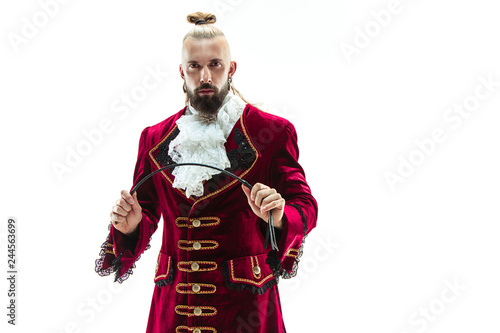 The young man wearing a traditional medieval costume of marquis posing at studio with whip. Fantasy, Antique, Renaissance concept