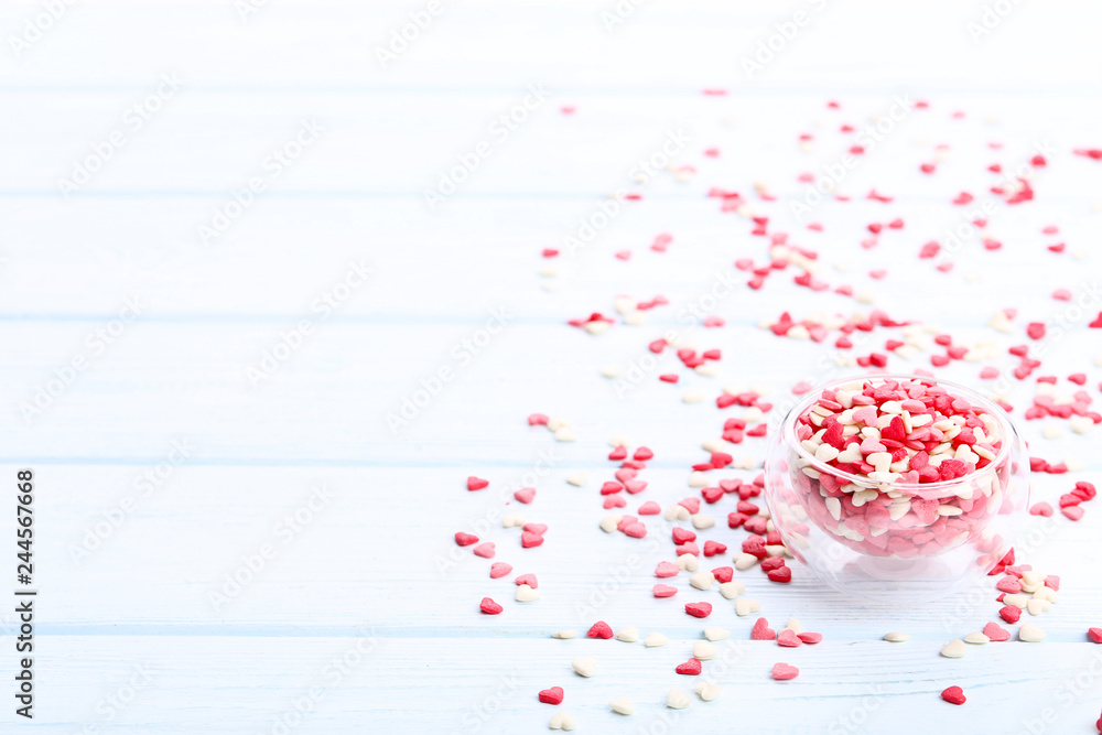 Heart shaped sprinkles in glass bowl on wooden table Heart shaped sprinkles in glass bowl on wooden table