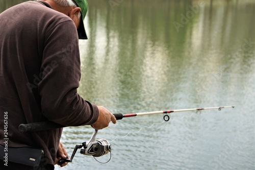 A seniorman holding a rod and reel fishing on the soft focus background of the pond and reflection, Spring in GA USA.