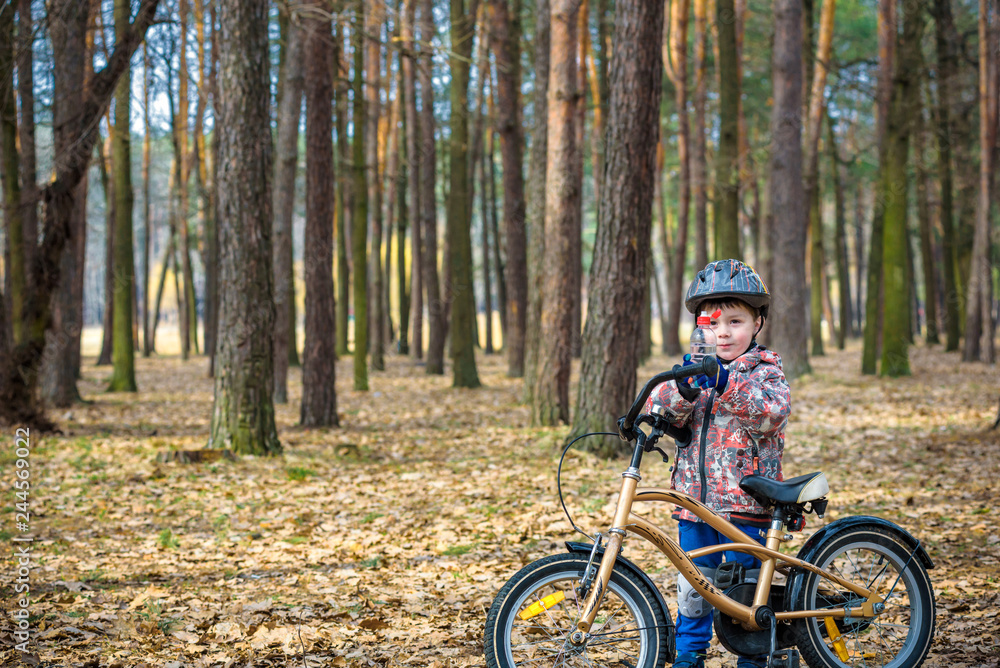 Fototapeta premium Young boy with bicycle with drinking clear water