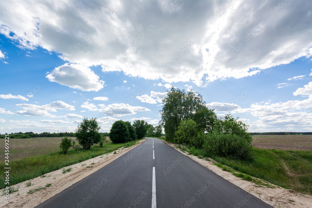 New asphalt road constructed in summer. Beautiful landscape of highway, trees and beautiful contrast sky with many clouds