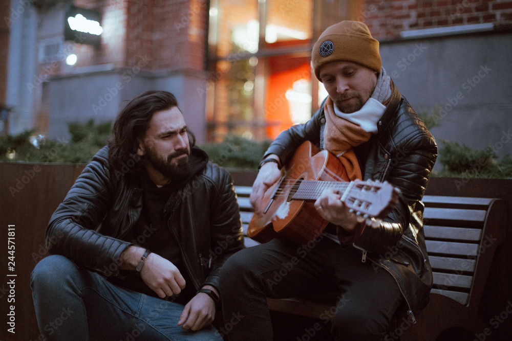 A company of friends on the bench plays the guitar. A company of friends on the bench plays the guitar.