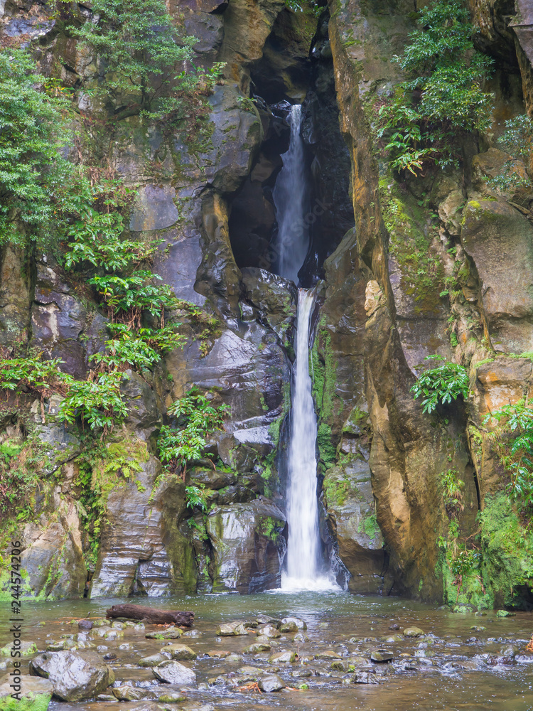Salto do Cabrito beautiful waterfall at hiking trail falling a from rock cave in green forest, Sao Miguel, Azores, Portugal Salto do Cabrito beautiful waterfall at hiking trail falling a from rock cave in green forest, Sao Miguel, Azores, Portugal