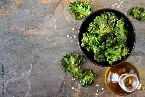 Healthy kale chips. Above scene, side border on a slate background. Copy space.